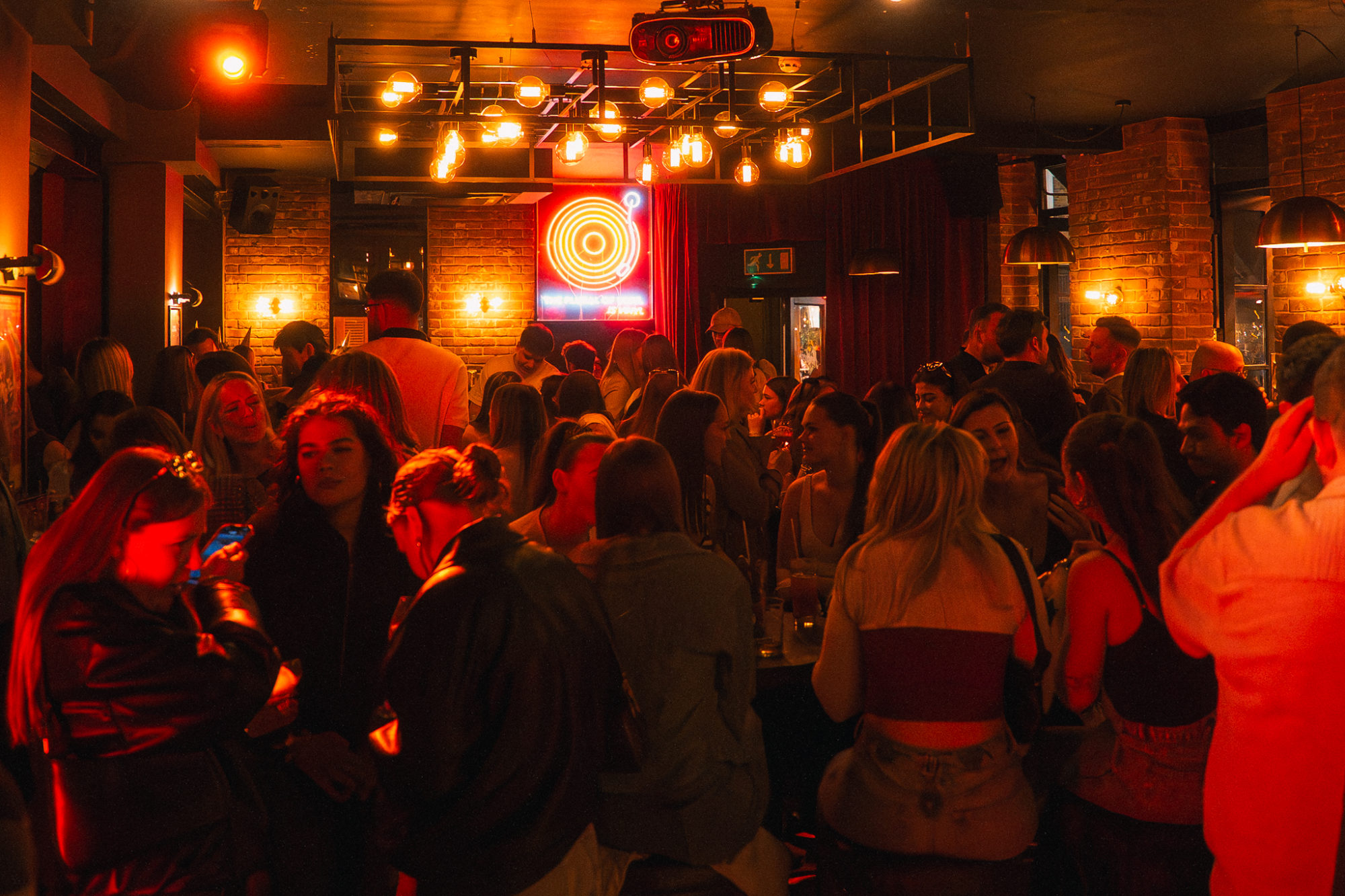 A group of people sitting down in a low lit live music venue.
