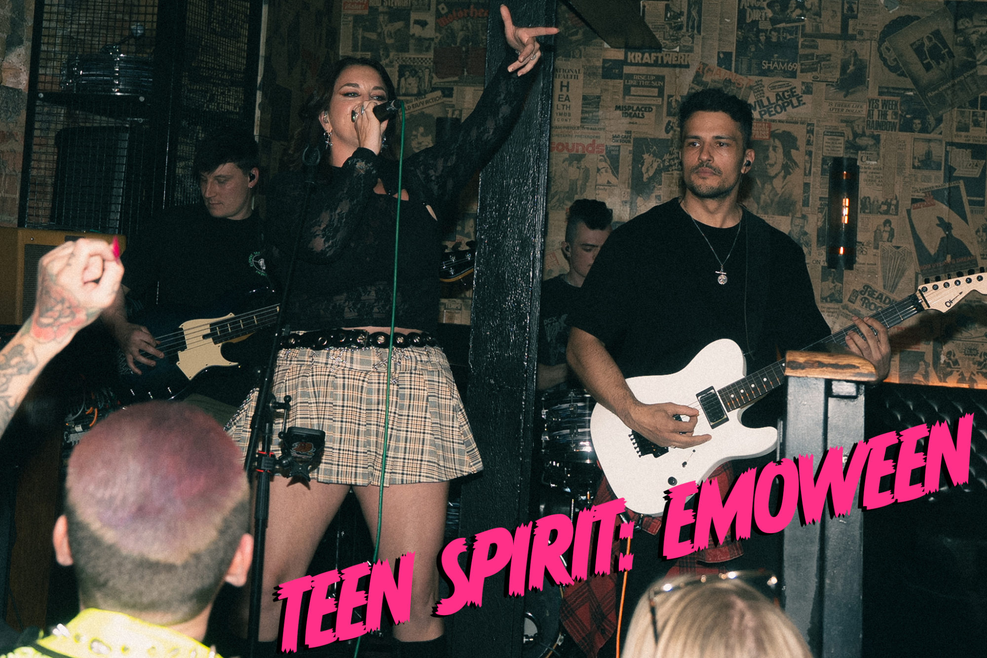 A punk pop band playing electric guitars and drums with a female lead singer.