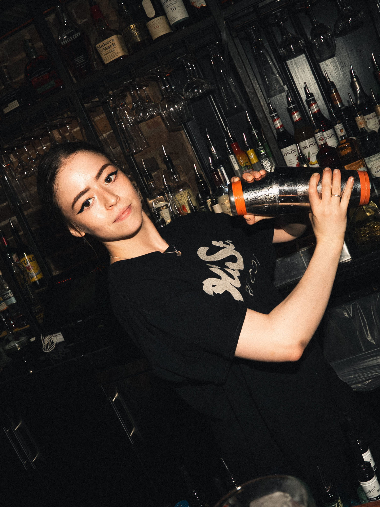 A female bartender making a cocktail using cocktail shakers.