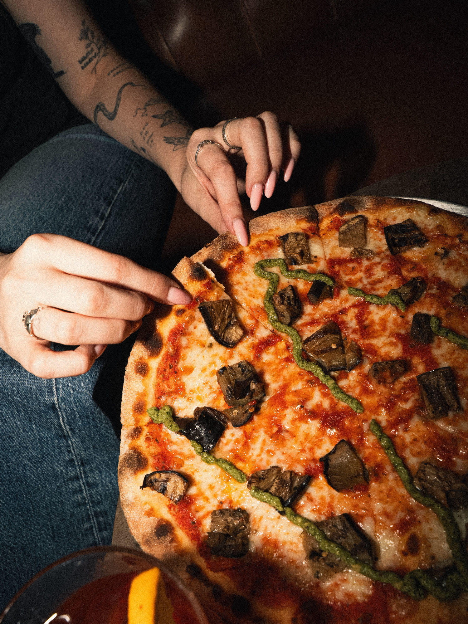 A person taking a slice of pizza.