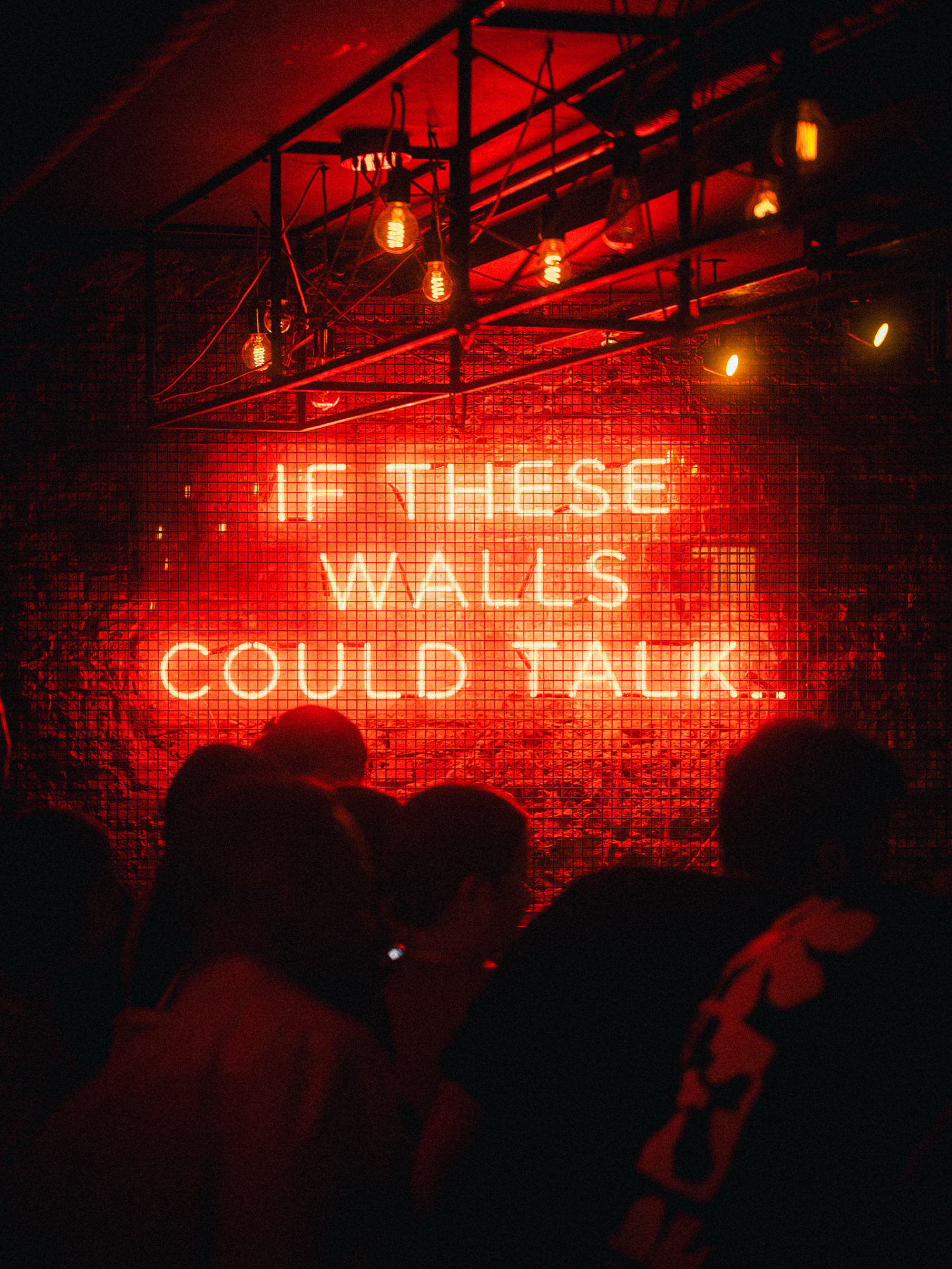 A red neon sign that says 'If these walls could talk'.